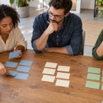 A small creative team grouping blank naming cards into distinct brand directions on a table